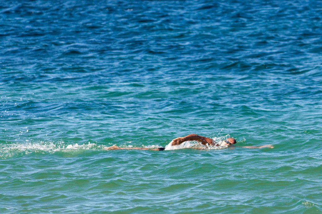 Tanned man swimming in a clear blue green ocean
